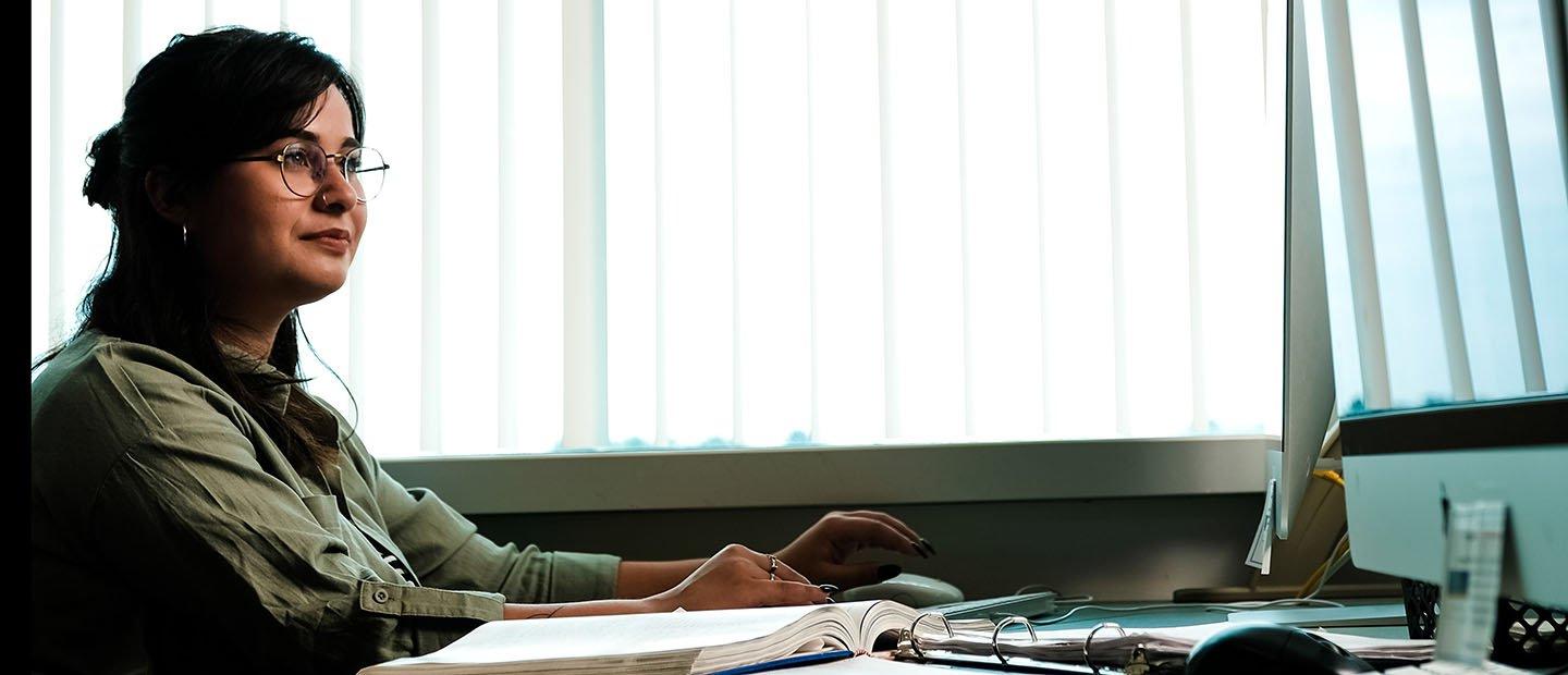 young woman sitting at a table with binders 和 books